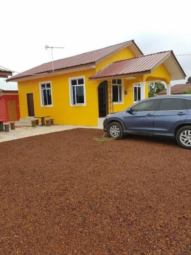 a car parked in front of a yellow house at Ria Homestay in Tanah Merah