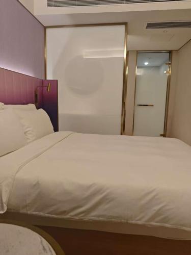 a bedroom with a large white bed and a mirror at Beijing Manxin Temple of Heaven North Gate Hotel in Beijing