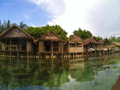 a group of wooden huts on the water at Subdikar Guest House in Sageurin