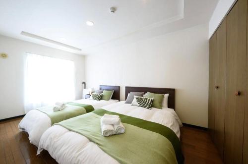 a bedroom with two beds with green and white sheets at Dynasty Palace Nijyuuyonken / Vacation STAY 7377 in Sapporo