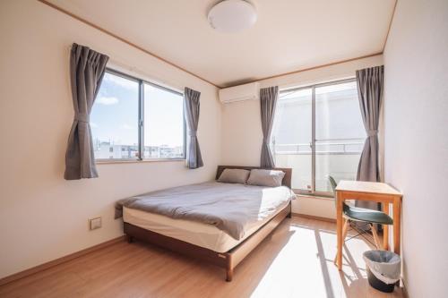 a bedroom with a bed and two windows at Okinawa - House / Vacation STAY 80468 in Okinawa City