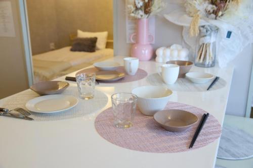 a table with plates and bowls and glasses on it at Maison Etoile 706 / Vacation STAY 7561 in Nagoya
