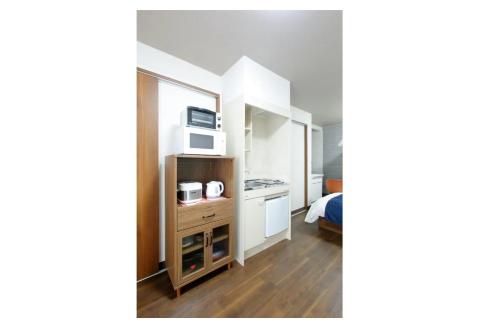 Kleines Zimmer mit einem Bett und einer Mikrowelle. in der Unterkunft Heights N7 / Vacation STAY 7568 in Sapporo