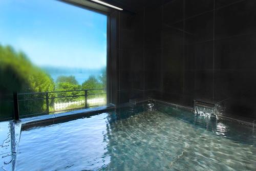 a swimming pool with a large window with water at Hotel Premium Lake TOYA in Lake Toya