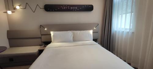a bed in a room with a sign on the wall at Atour Light Hotel Shanghai Xujiahui Jiaotong University in Shanghai