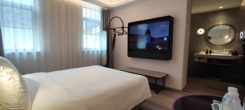 a hotel room with a bed and a flat screen tv at Atour Light Hotel Shanghai Xujiahui Jiaotong University in Shanghai