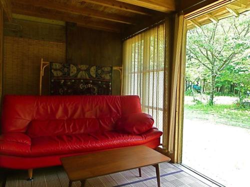 a red couch sitting in a room with a window at Kominka Sharehouse Hooju - Vacation STAY 7614 in Miyazaki