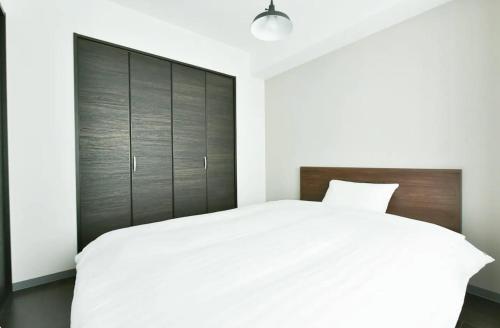 Suncourt Hondori Garden Hills / Vacation STAY 7592 في سابورو: غرفة نوم بسرير أبيض مع اللوح الخشبي