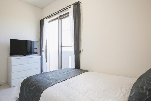 a bedroom with a bed and a tv and a window at Itoman - House / Vacation STAY 7483 in Itoman