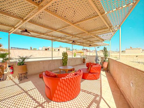 an outdoor patio with orange chairs and tables and a roof at Riad Timija in Marrakech