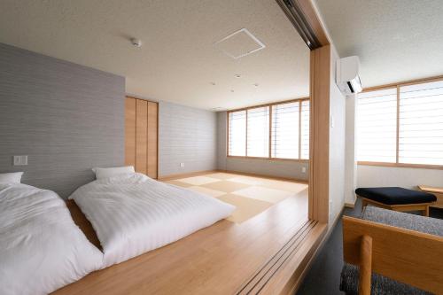 a bedroom with a white bed in a room with windows at BEYOND HOTEL Takayama 3rd - Vacation STAY 82217 in Takayama
