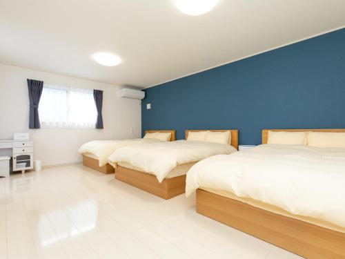two beds in a bedroom with a blue wall at Kinugawa Station Front room D in Nikko