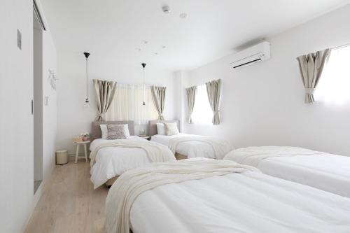 three beds in a room with white walls at Bijou Suites Sorriso - Vacation STAY 82795 in Osaka