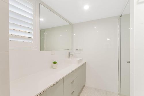 Un baño blanco con lavabo y espejo. en Pacific Gables 8, en Gold Coast