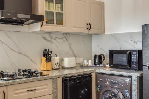 a kitchen with a washing machine and a microwave at Casa De Solares- New 2BHK Apartment with Pool Candolim in Pilerne