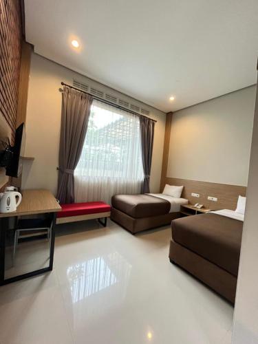 a hotel room with two beds and a window at Amerta Giri Hotel Dieng Wonosobo in Kejajar