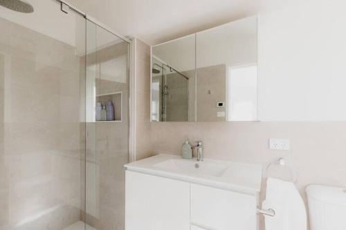 a white bathroom with a sink and a shower at Kelly Street Cottage in Historic Battery Point in Hobart
