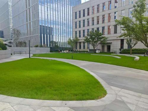a park in front of a building with a green lawn at Vienna International Hotel Xi'an Jinye Road Branch in Xi'an