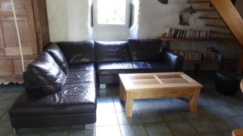 a black leather couch and a coffee table in a living room at Le Mas De La Siffleuse in Jaujac