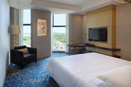 a hotel room with a bed and a chair and a television at Sheraton Changchun Jingyuetan Hotel in Changchun