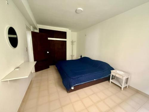 een slaapkamer met een blauw bed en een tafel bij Apartamento frente a Bahía de Pampatar in Pampatar