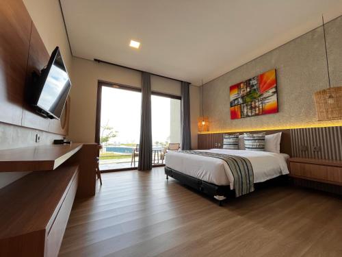 une chambre avec un lit et une télévision à écran plat dans l'établissement Tropical Beach Resort Sekongkang, à Sekongkang Bawa