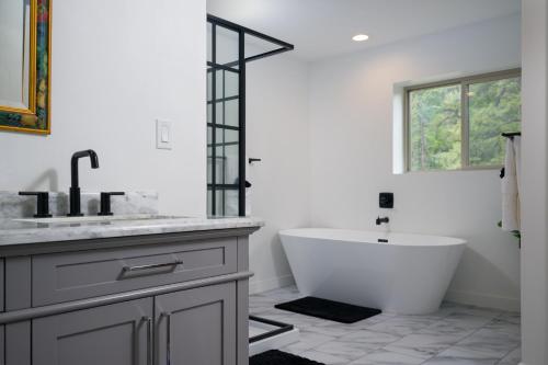 ein weißes Badezimmer mit Badewanne und Waschbecken in der Unterkunft Hot Tub + Views | Cozy Retreat in Pagosa Springs