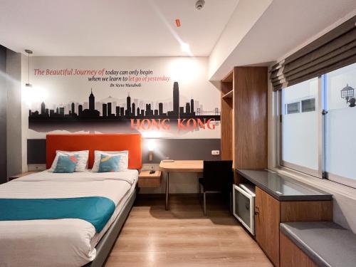 a hotel room with a bed and a desk with a sign at Sans Vibes Hotel Syariah Graha 100 Gubeng Surabaya in Surabaya