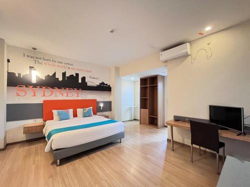 a bedroom with a bed and a desk and a television at Sans Vibes Hotel Syariah Graha 100 Gubeng Surabaya in Surabaya