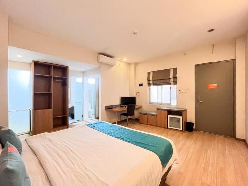 a bedroom with a large bed and a desk with a computer at Sans Vibes Hotel Syariah Graha 100 Gubeng Surabaya in Surabaya