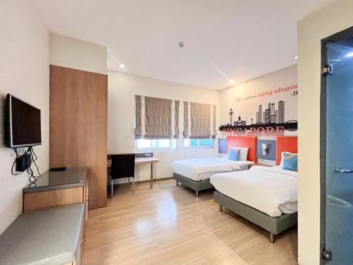 a hotel room with two beds and a flat screen tv at Sans Vibes Hotel Syariah Graha 100 Gubeng Surabaya in Surabaya