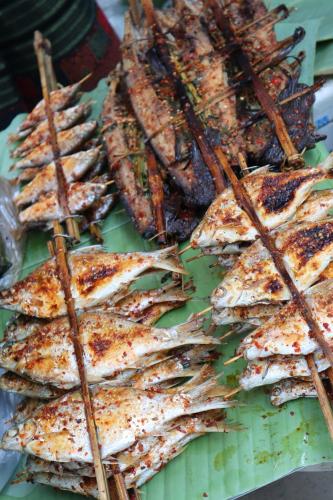 a bunch of food on a green plate with sticks at Dai House in Xishuangbanna Village in Menghan