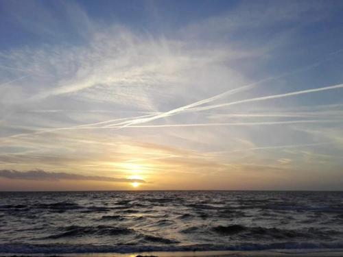 a sunset over the ocean with contrails in the sky at 6 person holiday home in Slagelse in Slagelse
