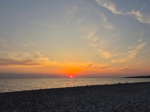 a sunset on the beach with the sun setting at 6 person holiday home in Slagelse in Slagelse
