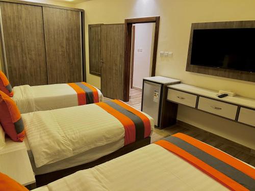 a hotel room with two beds and a flat screen tv at Sky Hotel in Aqaba