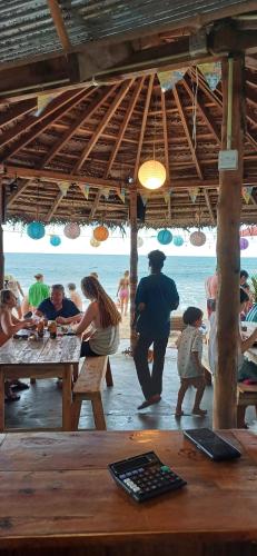 a group of people sitting at a picnic table on the beach at Surf & Turf in Arugam Bay