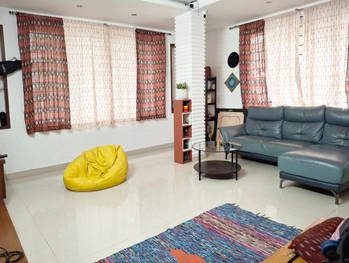 a living room with a blue couch and a yellow ottoman at Shepherd Stories - Community stay for Social Entrepreneurs in Hyderabad