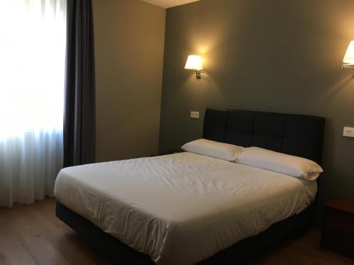 a bedroom with a bed with white sheets and a window at Hotel Gernika - Adults Only in Guernica y Luno