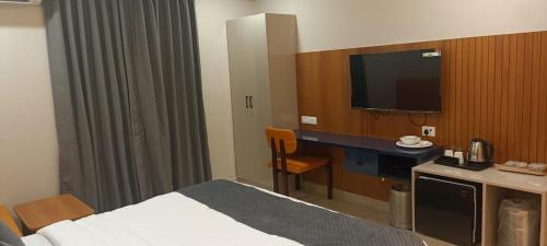 a hotel room with a bed and a flat screen tv at Vasatee Kondapur in Kondapur