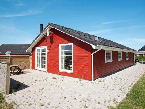 a red house with a patio in front of it at 8 person holiday home in Løkken-By Traum in Løkken
