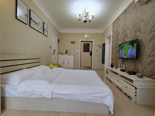 a bedroom with a white bed and a flat screen tv at Central Street River View Apartment in Harbin