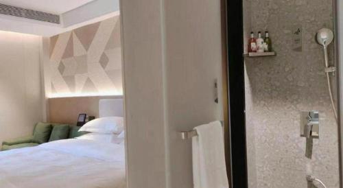 a bedroom with a bed and a bathroom with a shower at Borrman Hotel Chongqing Bishan Central Street in Chongqing
