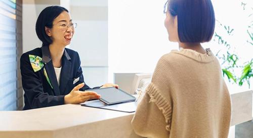 a woman sitting at a desk talking to a woman at Hotel Dream Gate Maihama in Chiba