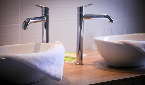 a sink and two faucets in a bathroom at Hotel Le Lion D'Or et Restaurant La Table Du Lion in Bayeux