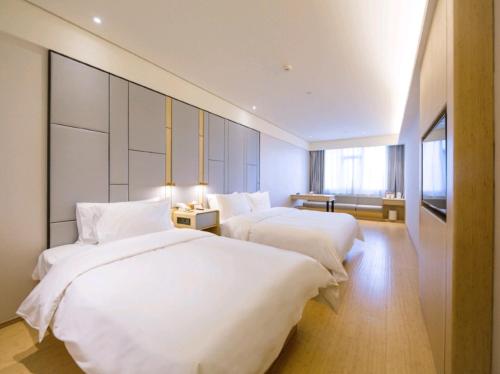 two beds in a hotel room with white sheets at JI Hotel Beijing South Railway Station Dahongmen in Beijing