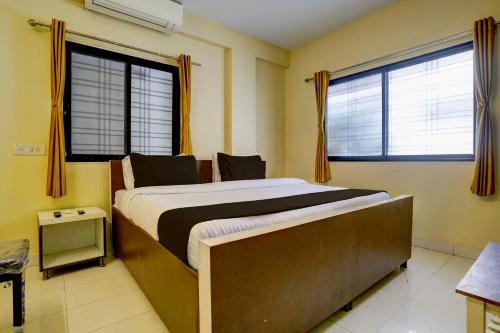 舍地Super Hotel O Sainagar Shirdi Railway Junction Formerly Sai Vyankatesh Residency的一间带一张大床和两扇窗户的卧室