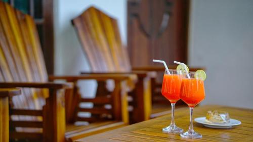 two glasses of orange juice sitting on a wooden table at Dambullu Dreams Stay in Dambulla