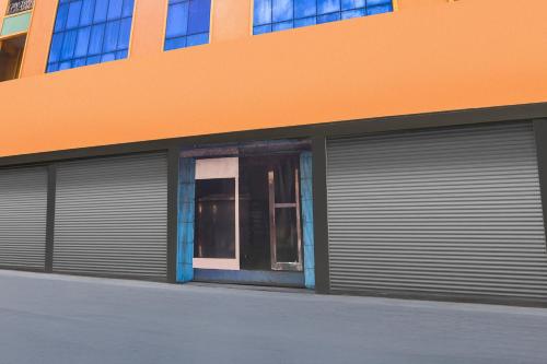 an orange building with two garage doors on a street at Hotel O Rayagada Downtown in Rāyagada