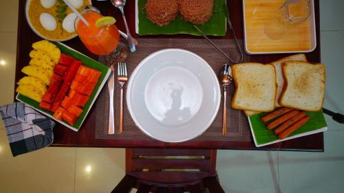 a table with a plate of bread and fruit and vegetables at Dambullu Dreams Stay in Dambulla