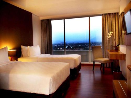 a hotel room with two beds and a large window at Arch Hotel Bogor in Bogor